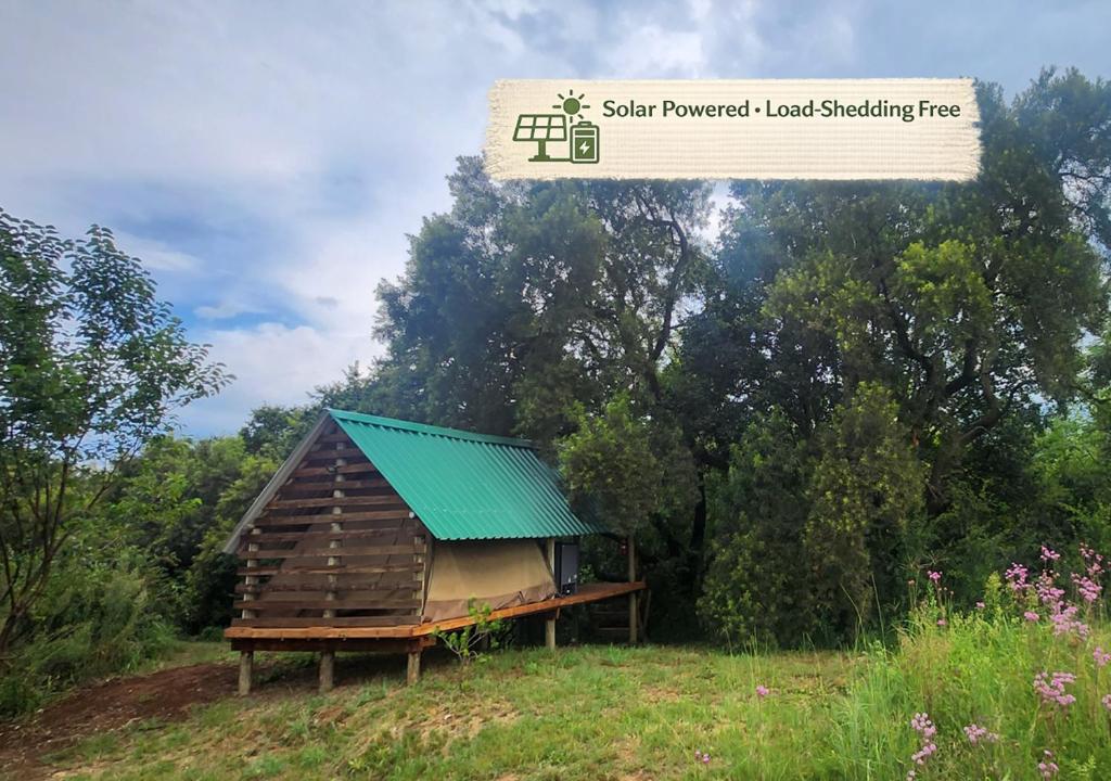 a small house with a green roof in a field at Jackal Cry River View Tent in Skeerpoort