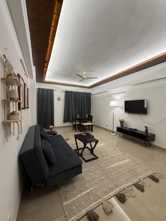 a living room with a black couch and a table at Shiva Stays - Make yourself at home in Lucknow