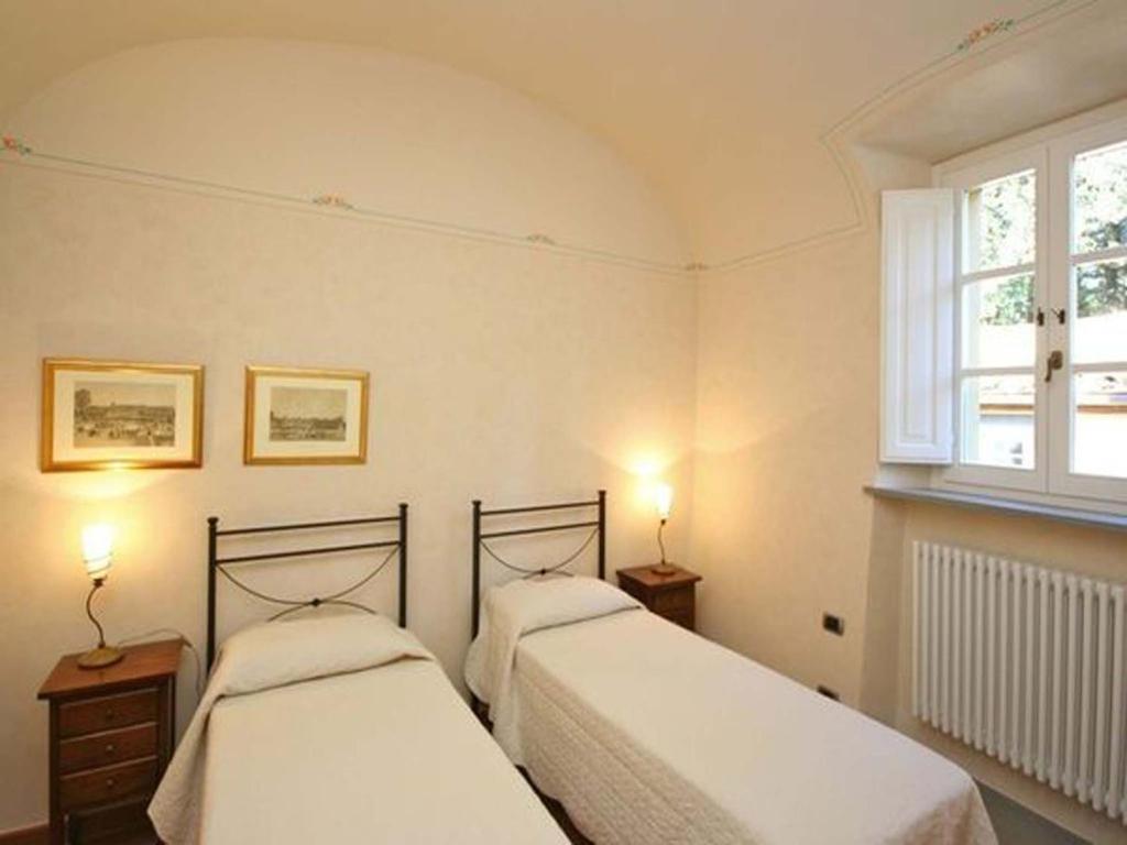 2 łóżka w sypialni z oknem w obiekcie Relais Villa Sensano w mieście Pignano