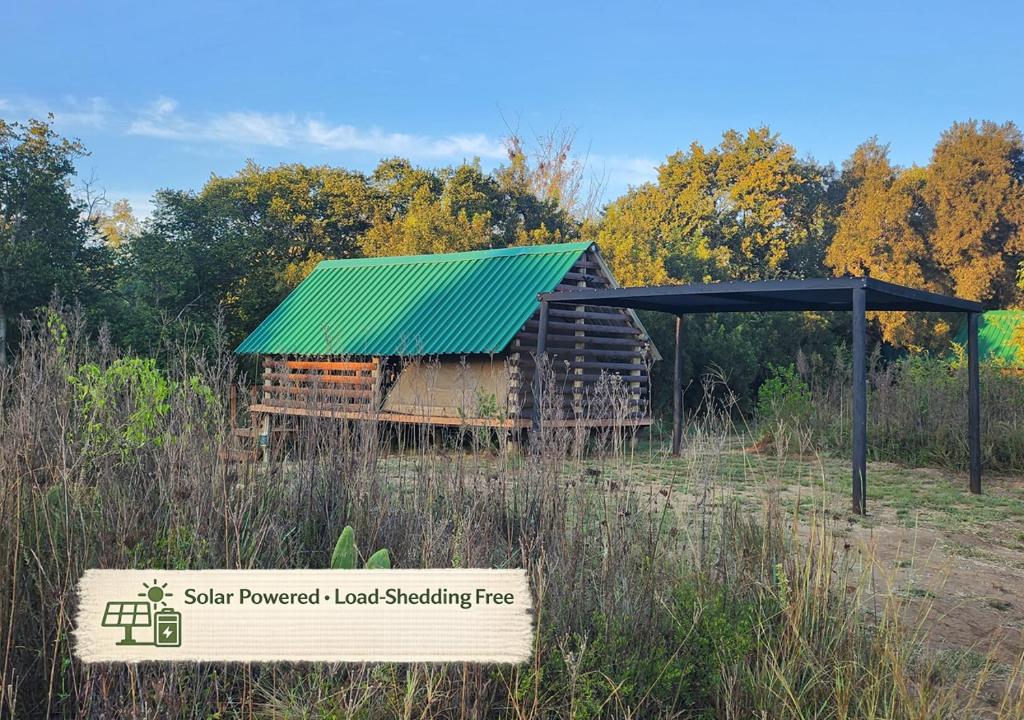 a sign in front of a log shed with a green roof at Porcupine River View Tent in Skeerpoort
