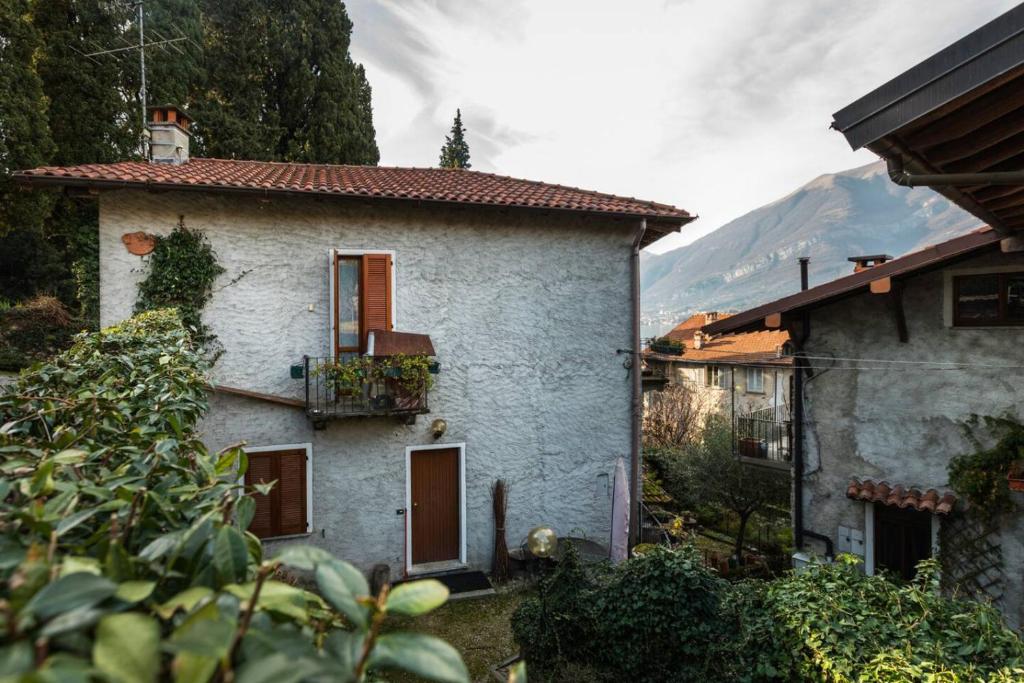 a small white house with a mountain in the background at Loppia Bay View Apartment in Bellagio