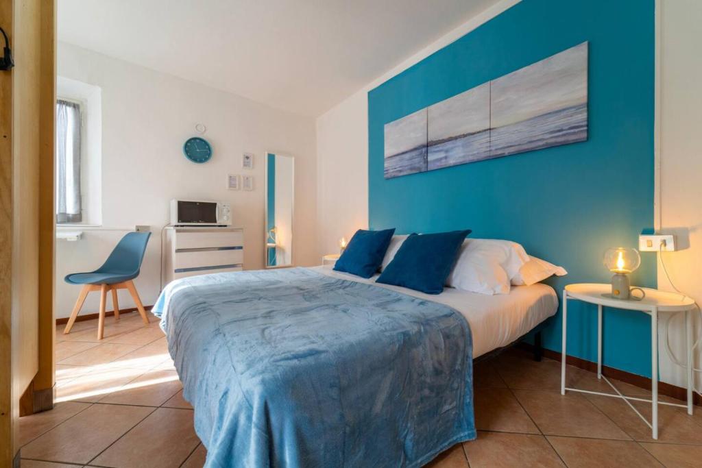 a bedroom with a large bed with a blue wall at Azure Comfort Studio in Bellagio