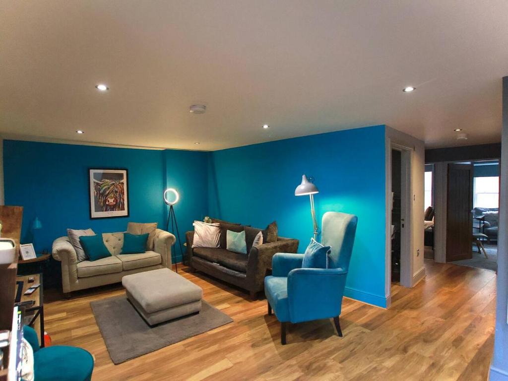 a living room with blue walls and blue furniture at Spacious 2BR with garden in Alnwick