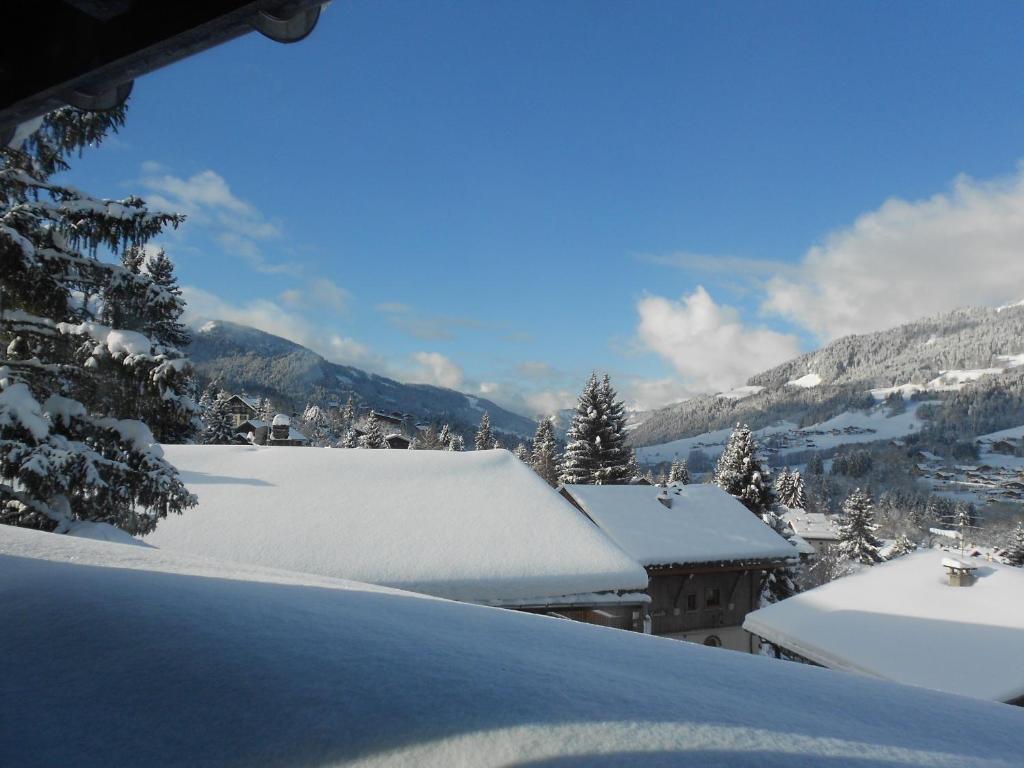 a snow covered roof of a house with mountains in the background at Au Coin Du Feu in Megève