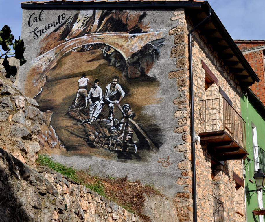 a mural on the side of a building with people on it at Cal Tresonito in Coll de Nargó