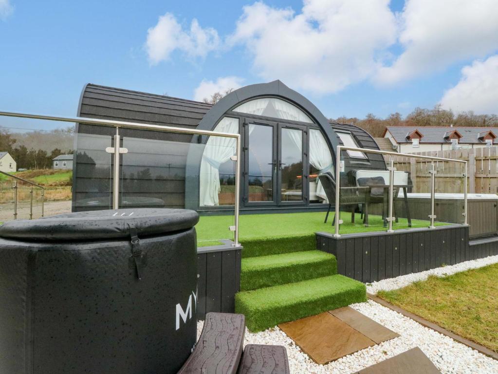 a house with a green lawn and a glass house at Crofters Suite in Acharacle
