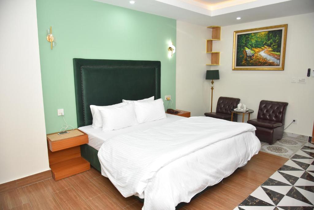 a bedroom with a large white bed and two chairs at Bridge Residency River View Hotel Near Bridge,201 in Muzaffarabad