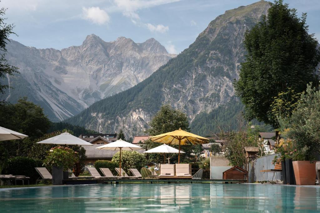 a swimming pool with chairs and umbrellas in front of mountains at Valavier Aktivresort in Brand