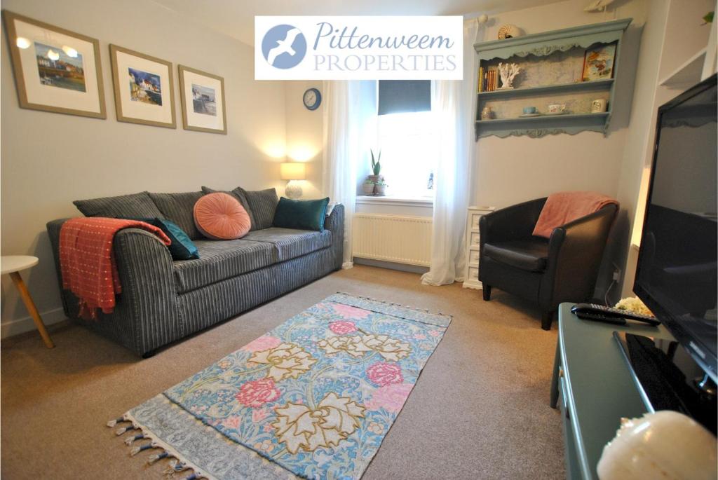 a living room with a couch and a television at Sandpiper Cottage- Coastal hideaway in Anstruther