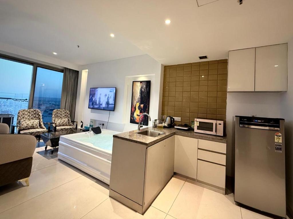 a kitchen and a living room with a microwave at Luxe jacuzzi studio key 2 in Gurgaon