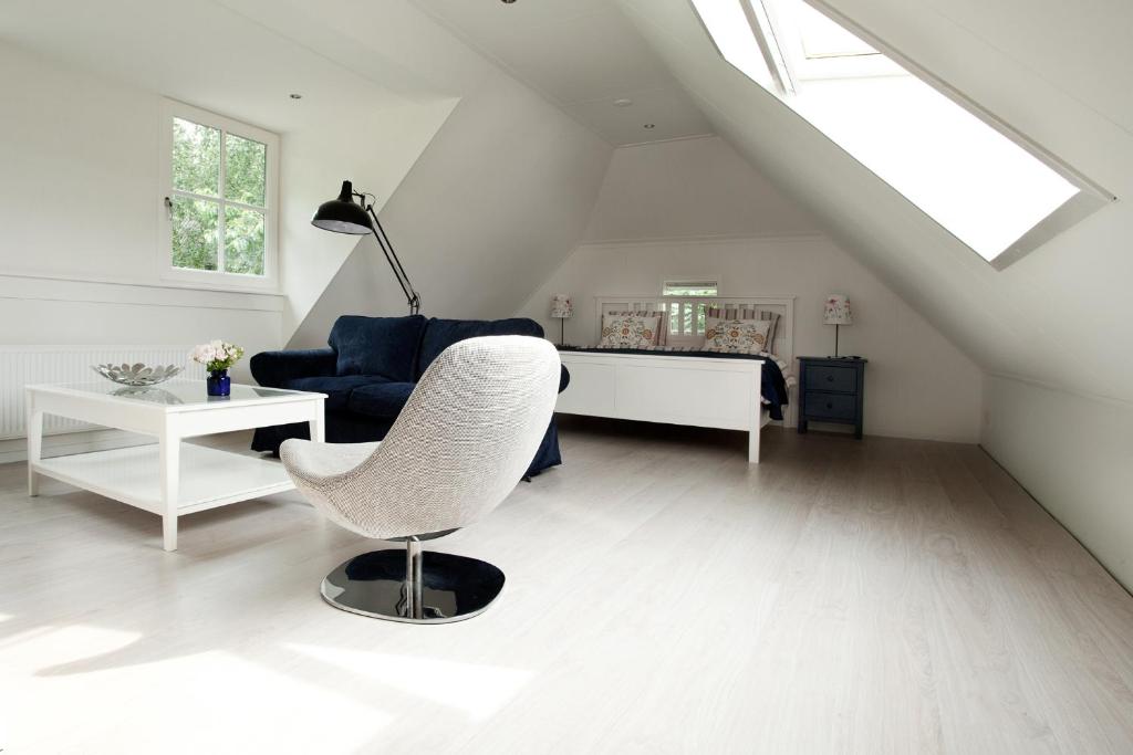 een witte woonkamer met een stoel en een bank bij B & B De Lorijn in Duiven