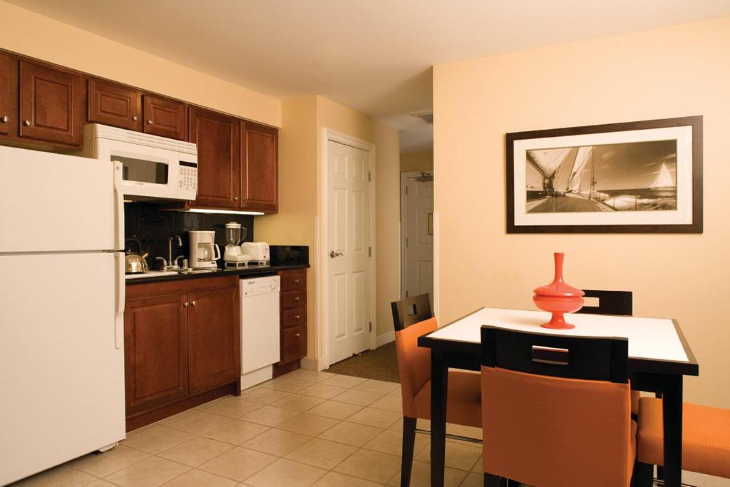 a kitchen with a white refrigerator and a table at Club Wyndham Harbour Lights in San Diego
