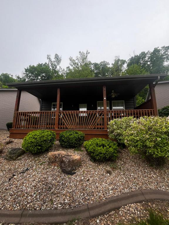 a house with a deck with bushes in front of it at Papa Chubbys RV Resort in Sunrise Beach