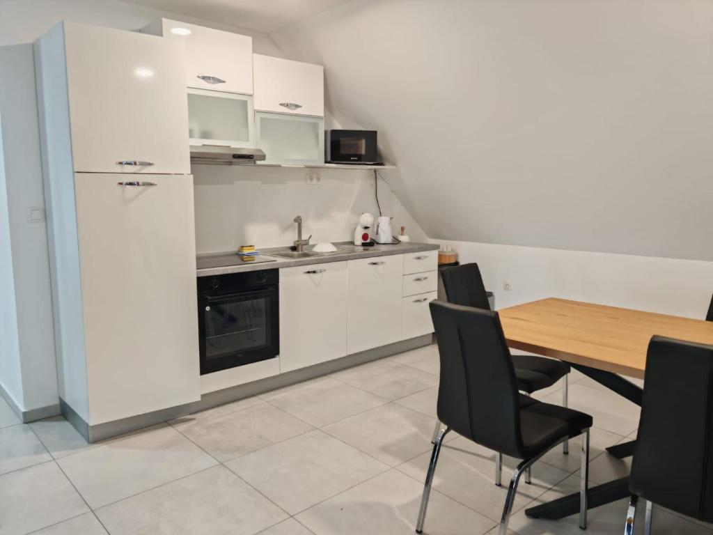 a kitchen with white cabinets and a table with chairs at Apartma pod Tremi Kralji in Oplotnica
