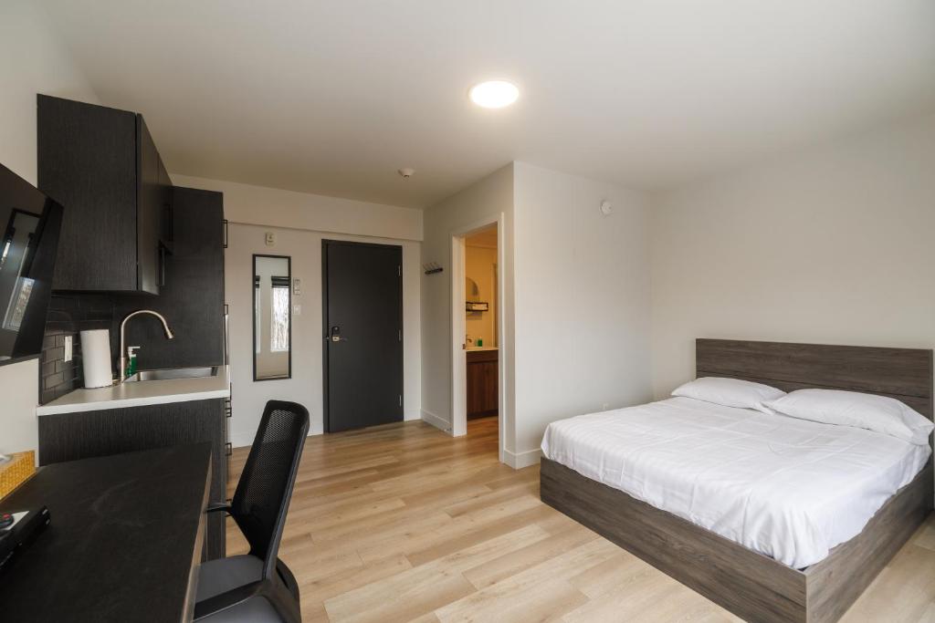 a bedroom with a bed and a desk and a kitchen at Complexe la Falaise in Rivière-du-Loup