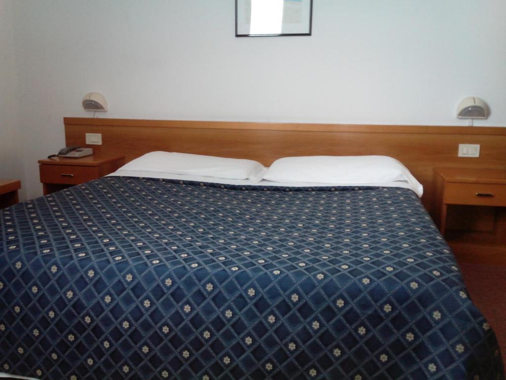 a bedroom with a bed with a blue and white comforter at Hotel Niki in Tribiano