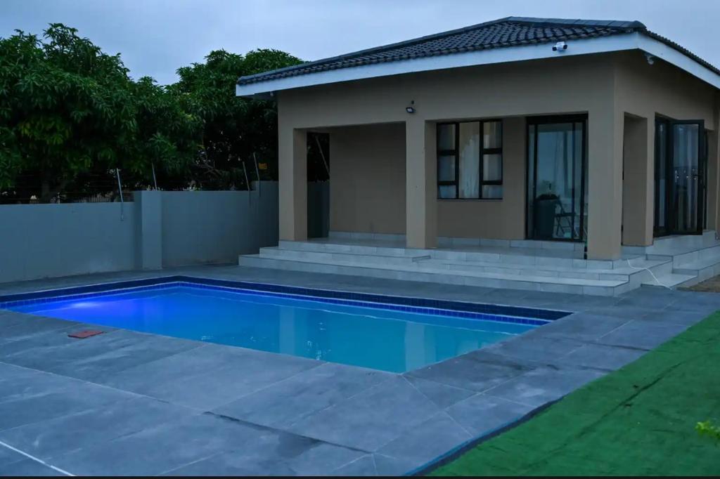 a swimming pool in front of a house at Mjee's Guest House in Ulundi