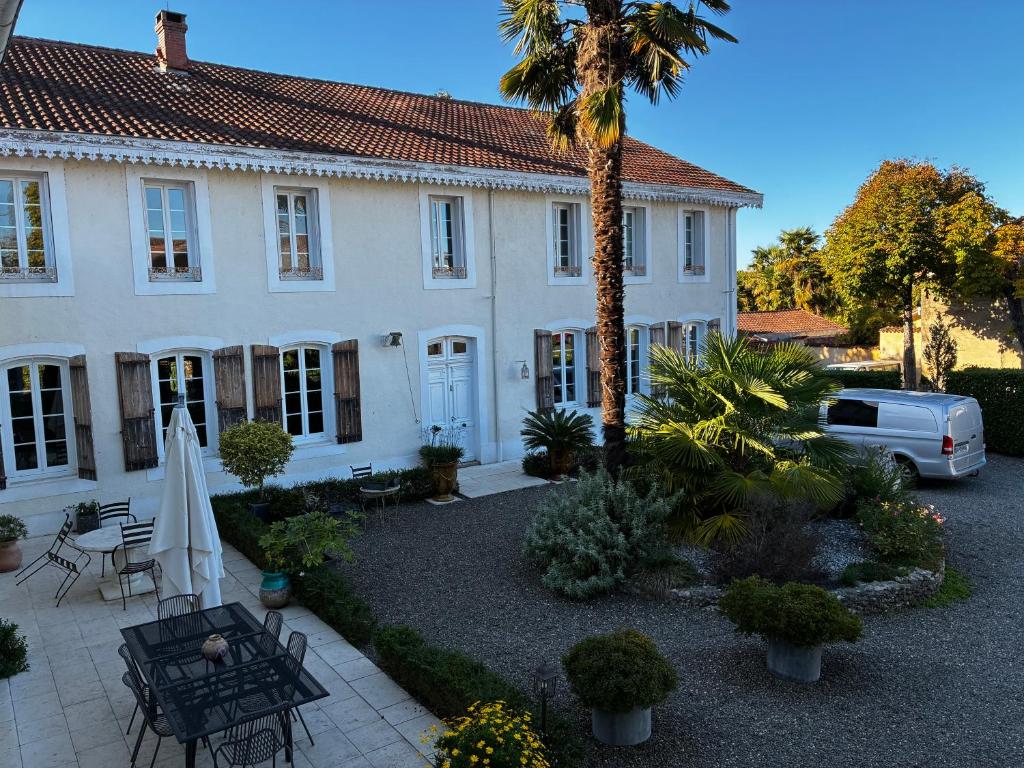 a white house with a palm tree in front of it at Maison d'Hôtes Lassaubatju in Hontanx