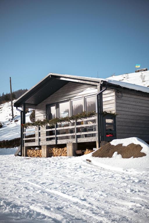 a house with a porch in the snow at Familyhata in Dzembronya