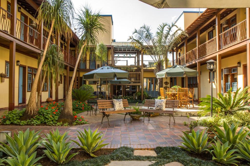 a courtyard with tables and chairs and palm trees at Pousada Rotunda in São João del Rei