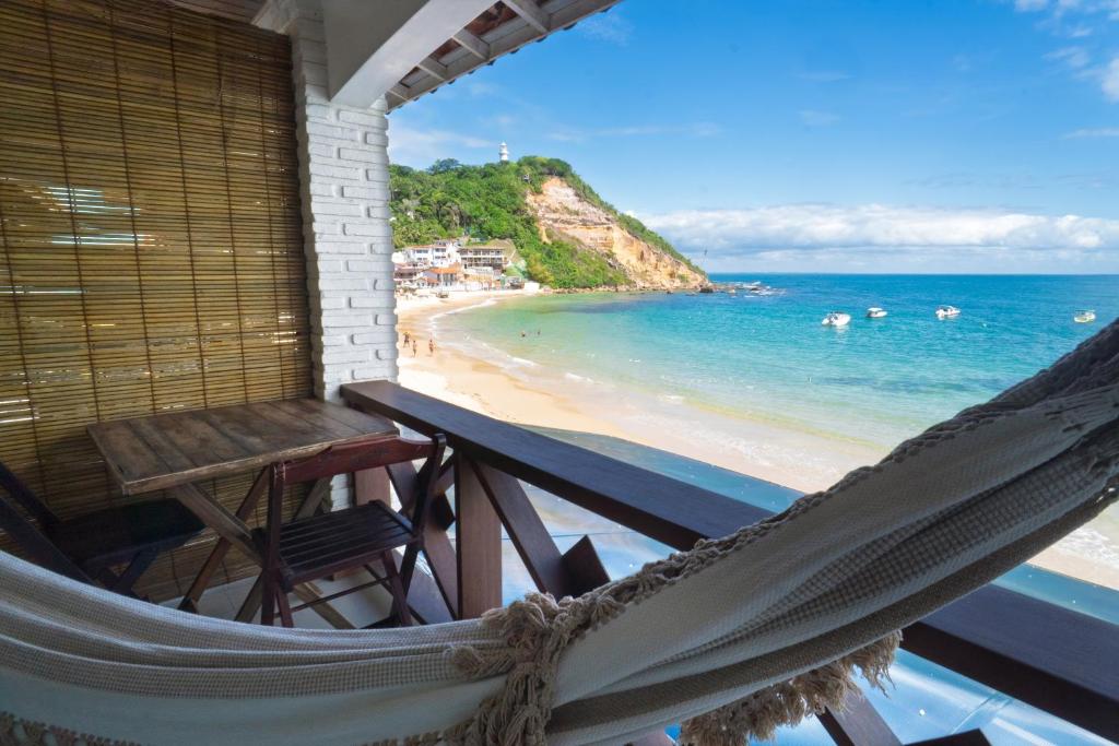 a hammock on a balcony with a view of the beach at Pousada Porto 23 in Morro de São Paulo