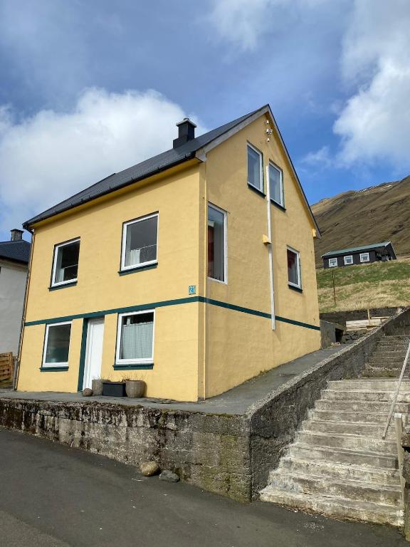 a yellow house sitting on the side of a street at Ocean view from front parquet in Oyndarfjørður