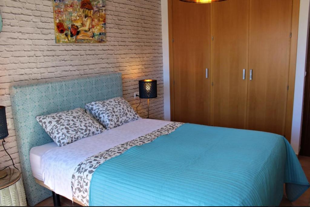 a bedroom with a bed with a blue comforter at Hostal Don Peque in Nerja