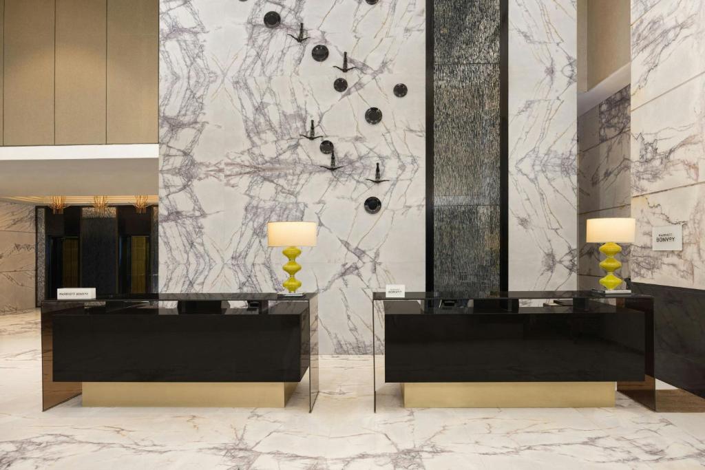 a lobby with two mirrors and a marble wall at Courtyard by Marriott Bilaspur in Bilāspur