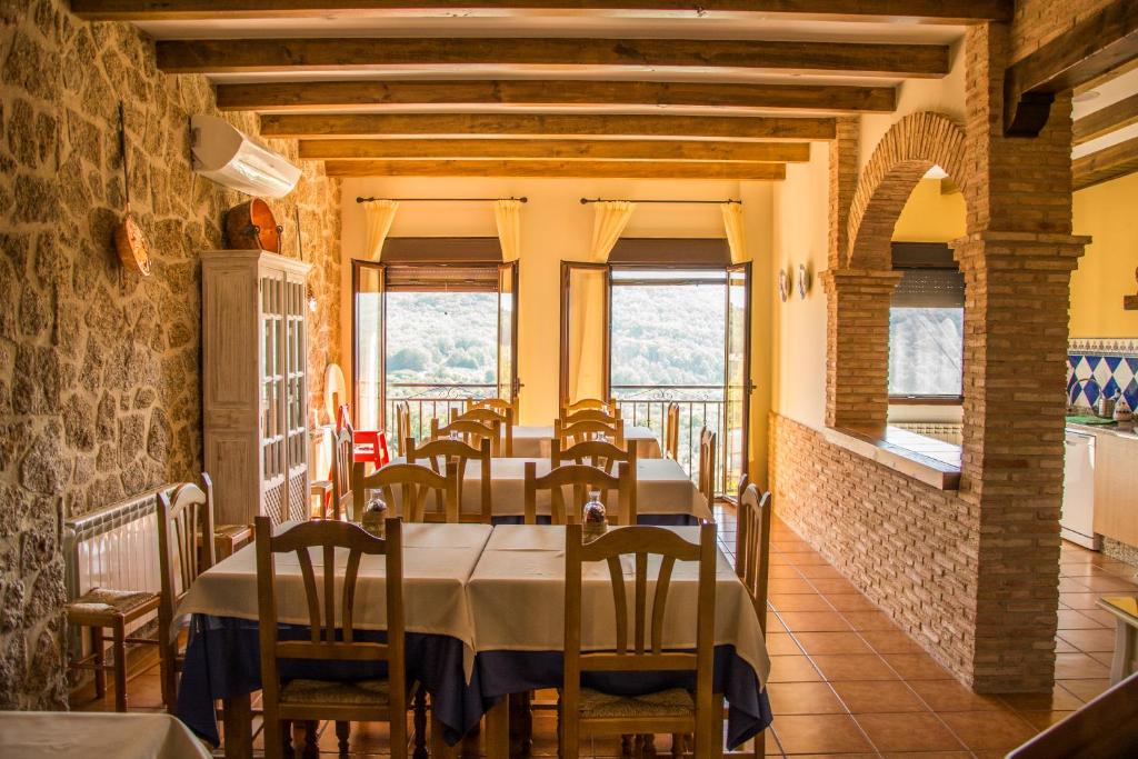 un comedor con mesas, sillas y ventanas en Casa Rural Fuente El Boticario, en Aldeanueva de la Vera