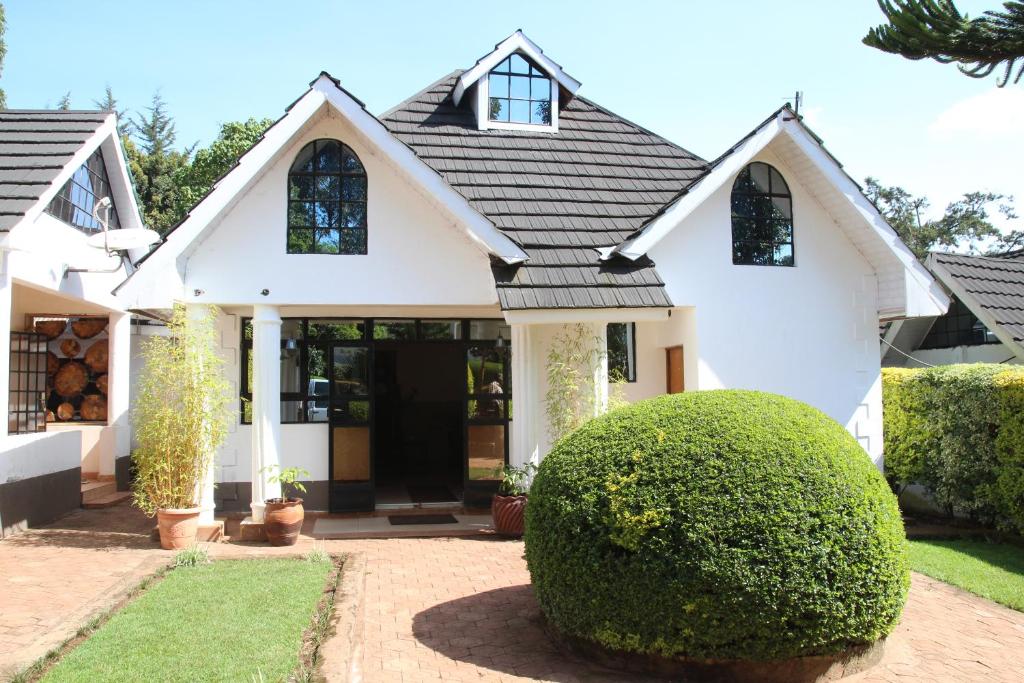 a white house with a bush in front of it at Sahara Gardens-Kericho in Kericho