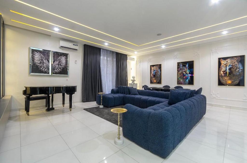 a living room with blue couches and a piano at Olaz holmes in Lagos