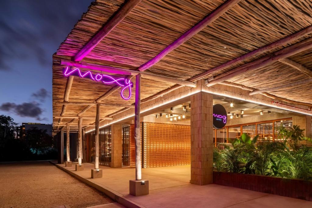 a building with a purple neon sign on it at Moxy Tulum in Tulum