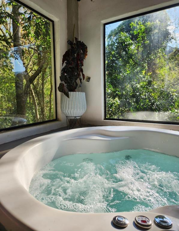 a bath tub with water in it with two windows at Studio Mata dos Curiós in Petrópolis