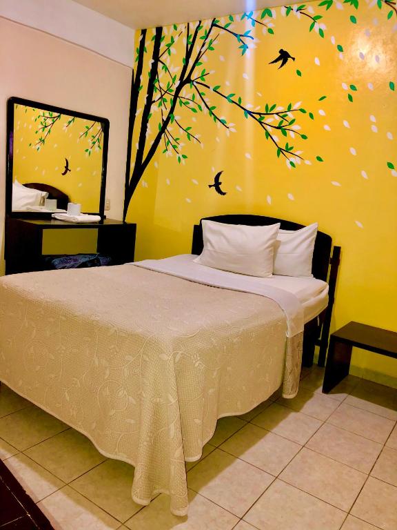 a bedroom with a bed with a tree painted on the wall at Hotel MERLI in Asunción Nochixtlán