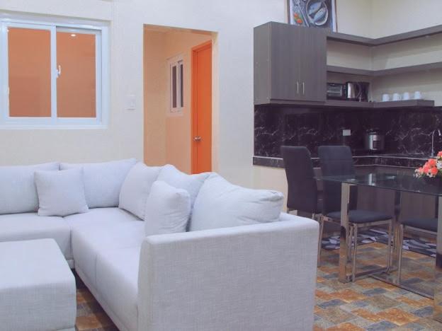 a living room with a white couch and a table at Rubi's House in Ilayang Talim