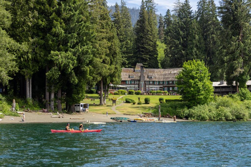 two people in a red boat on a lake with a building at Lake Quinault Lodge in Quinault
