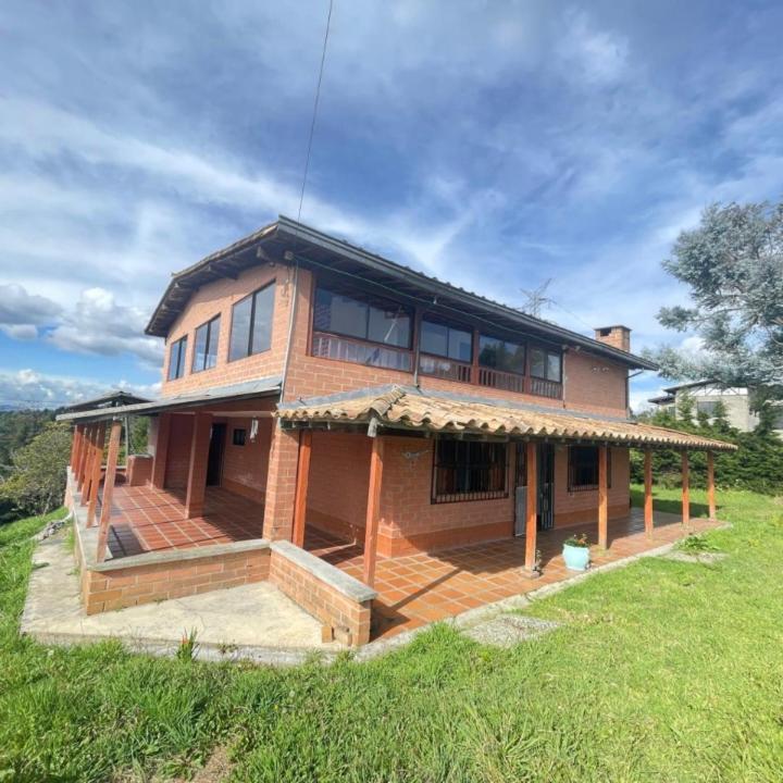 a large brick house on top of a green field at Casa Campestre Familiar in Medellín