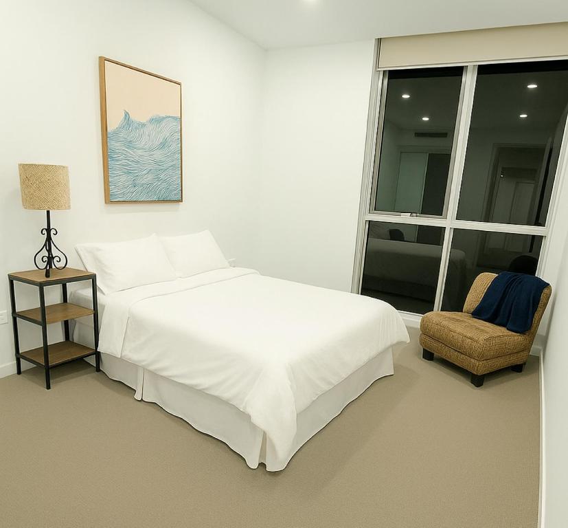 a white bedroom with a bed and a chair at Cozy Suite in Schofields in Schofields