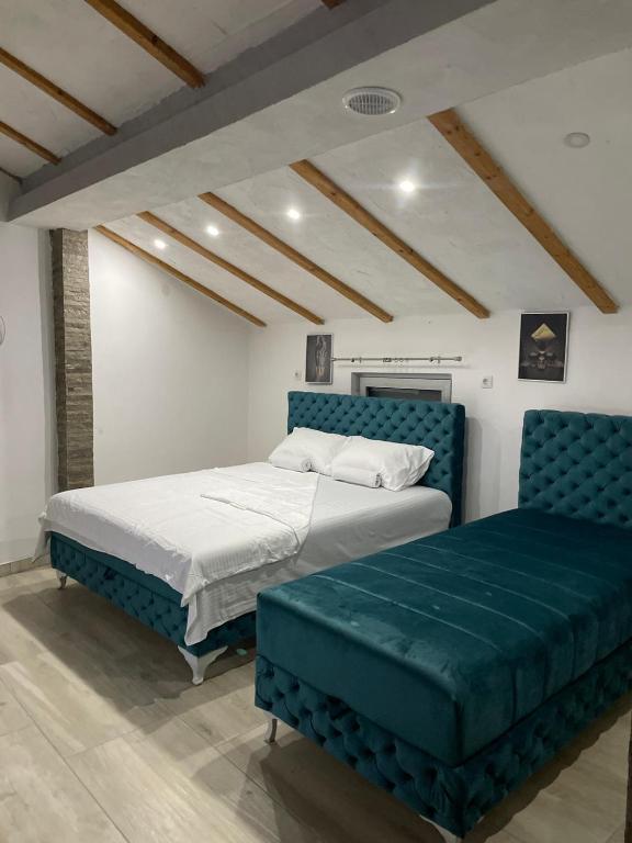 a bedroom with two beds and a blue couch at Yugoslavija Lux 3 in Aleksandrovac