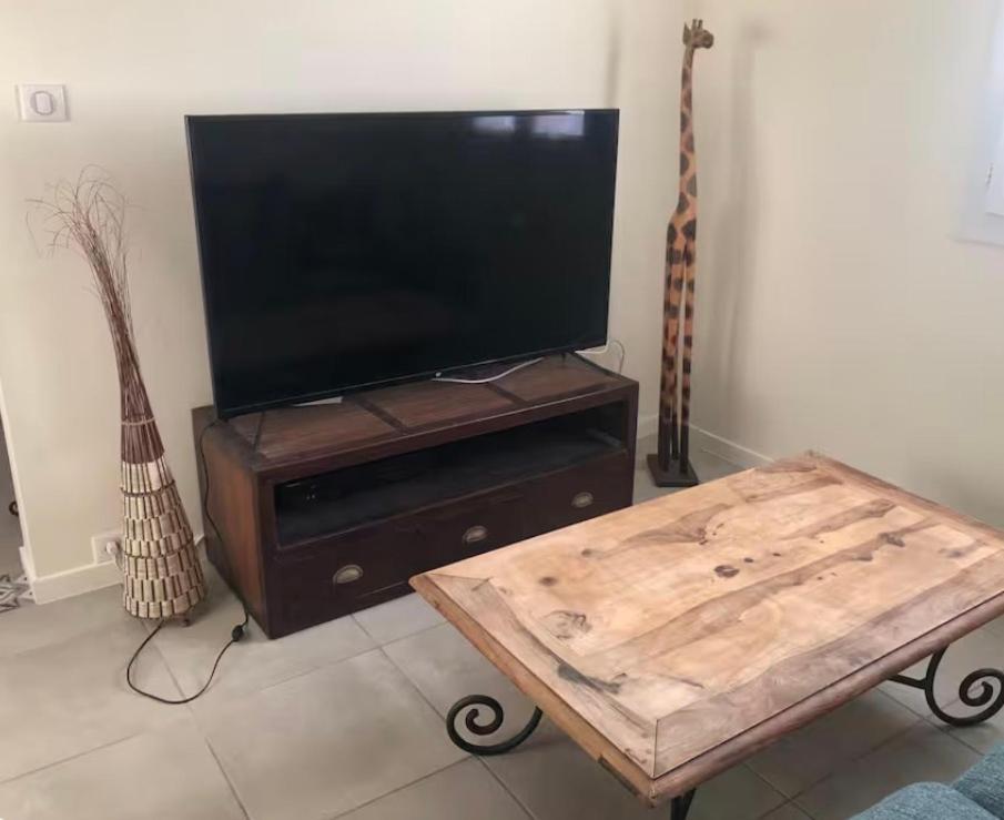 a flat screen tv on a wooden stand with a coffee table at Gîte Ruoms in Ruoms