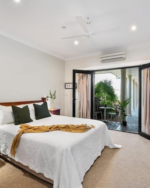 a white bedroom with a large bed and a balcony at Mudgee Gardens Stayz in Mudgee