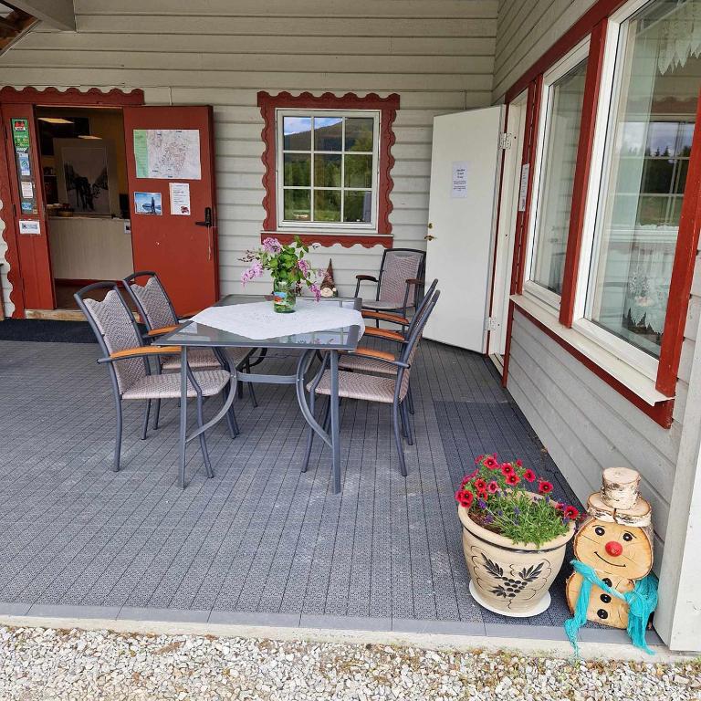 a patio with a table and chairs and a pot of flowers at Svenningdal Camping in Svenningdal