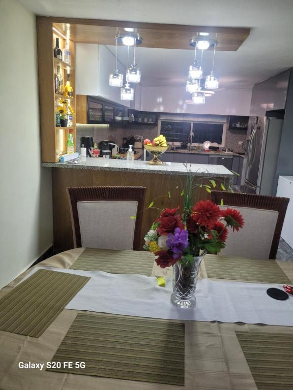 a dining room table with a vase of flowers on it at bienvenido a casa in San Pedro de Macorís