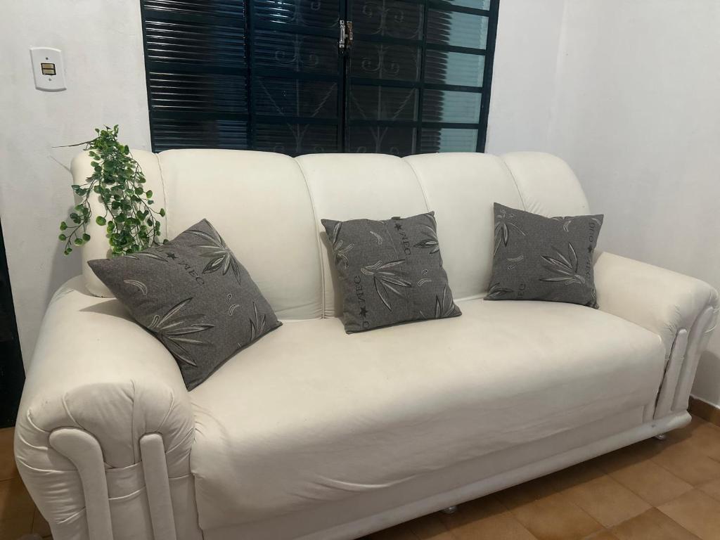 a white couch with four pillows on it at E Lindo Sobrado com 2 quartos em condomínio - Centro in Marília