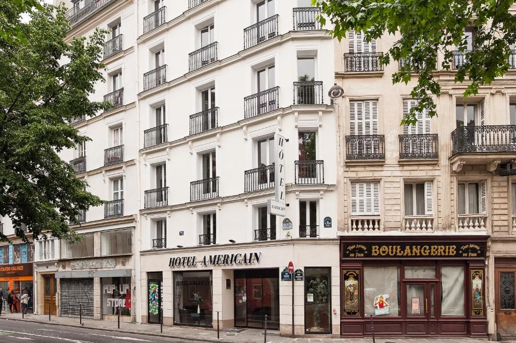 - un grand bâtiment blanc dans une rue de la ville dans l'établissement Hotel Americain, à Paris