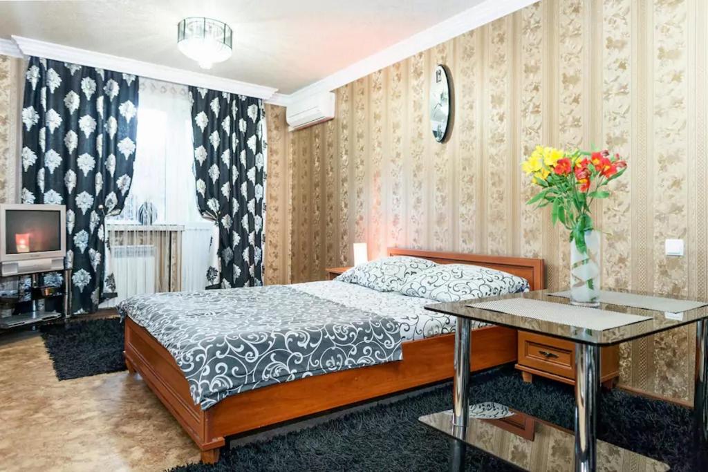 a bedroom with a bed and a table with a vase of flowers at Apartment on Nezalezhnoy Ukrаiny near Intourist Hotel in Zaporozhye