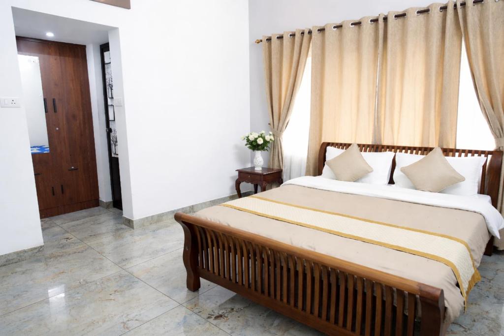 a bedroom with a bed and a window with curtains at PATHIRAMANAL Service Villas in Alleppey