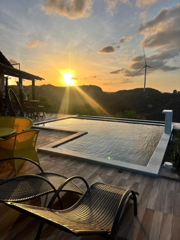 a swimming pool with chairs and the sunset in the background at Margarida 01 in Monte das Gameleiras