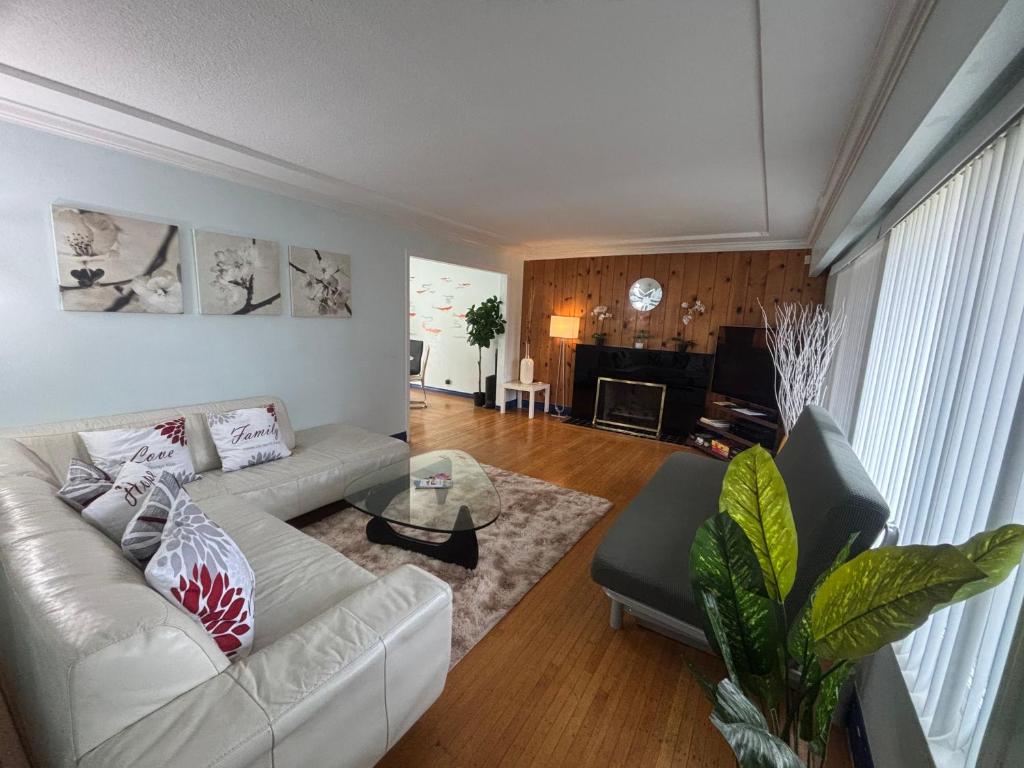 a living room with a white couch and a table at Charming Bright 3BR House - Upper Level Suite in Burnaby