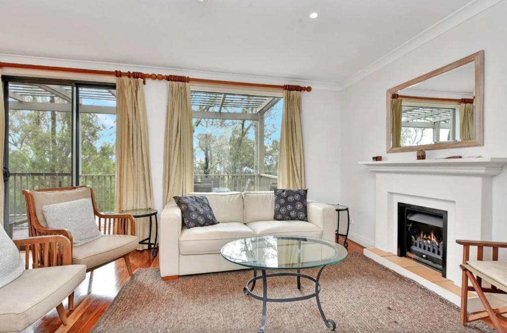 a living room with a couch and a fireplace at Villa Rose with Free Wine Tasting Included in Pokolbin